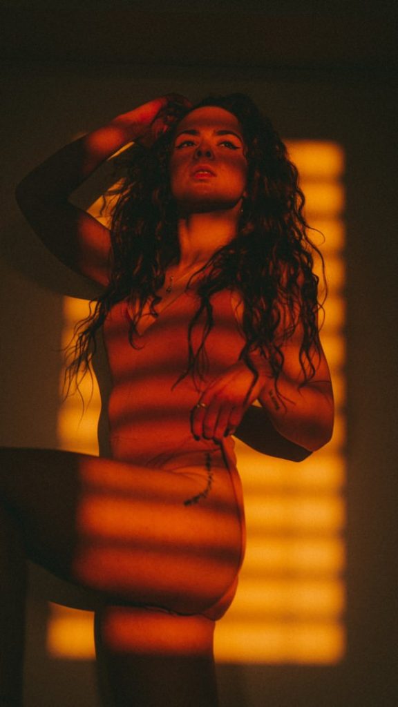 Portrait of a model with a hip tattoo photographed in golden evening sunlight during an available light photoshoot.