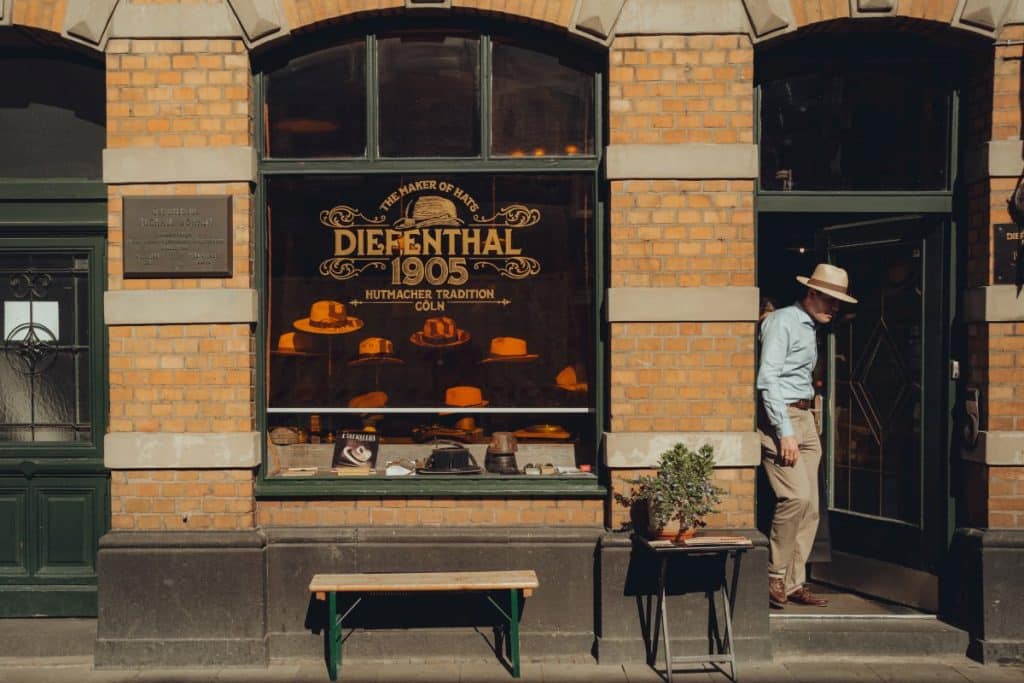 Stylish man with a hat leaving a traditional hat shop in a beautifully restored historic building.