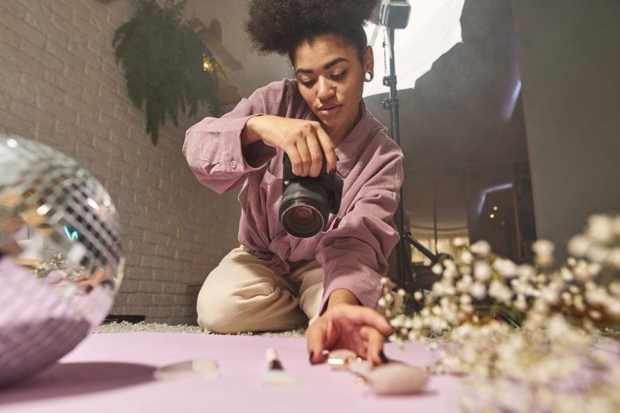 Female,Photographer,Take,Photo,Of,Disco,Ball,,Jade,Roller,,Face Female photographer take photo of disco ball, jade roller, face brush, ice and blossom tree branch on digital camera at home studio. Content for photostocks, commerce, social networks and advertising