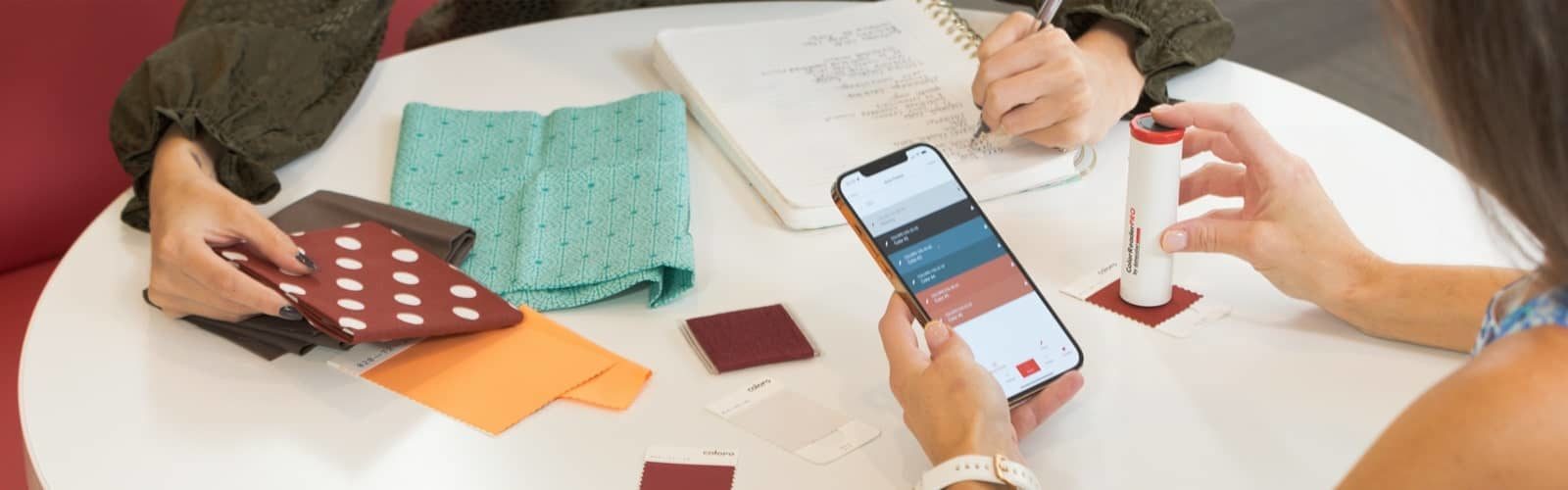 person using phone and looking at color swatches at a table