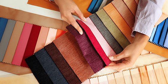 A person comparing swatches of different colored fabrics.
