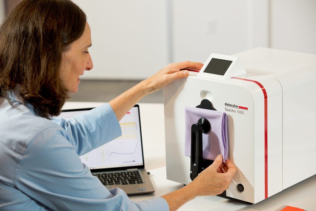 Woman measuring color on a textile sample using a Datacolor spectrophotometer.