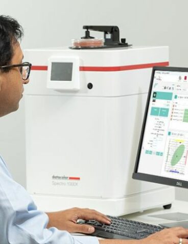 A man using a formulation software next to a spectrophotometer.